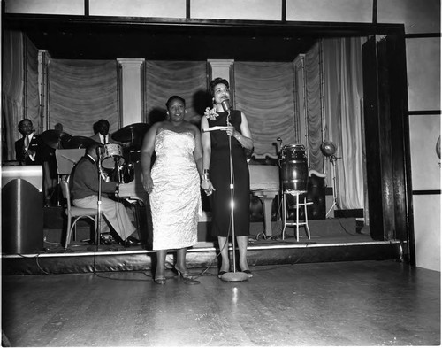 Fashion and hair show participants standing at a microphone at Ciro's, Los Angeles, 1957