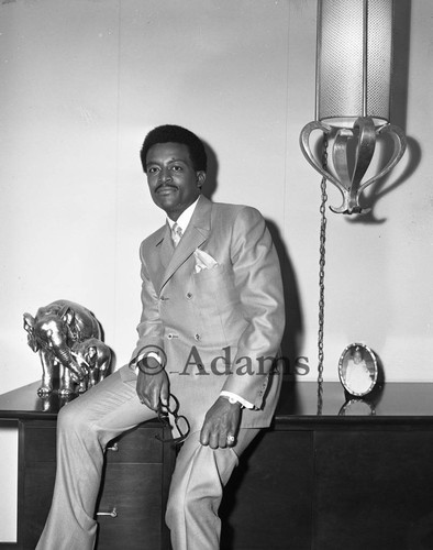 Attorney Johnnie Cochran sits on a desk, Los Angeles, 1969