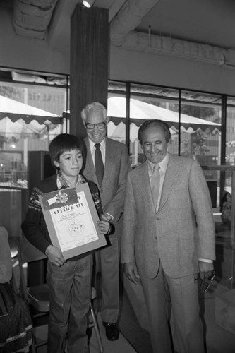 Children's museum event guests William Hanna and Joseph Barbera posing with a young award winner, Los Angeles, 1982