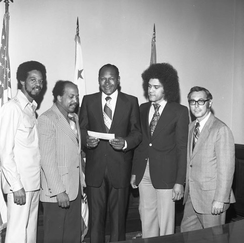 Tom Bradley receiving a check from KGFJ and Motown representatives, Los Angeles, 1974