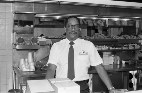 Chicken Charlie's restaurant manager posing behind the counter, Los Angeles, 1987