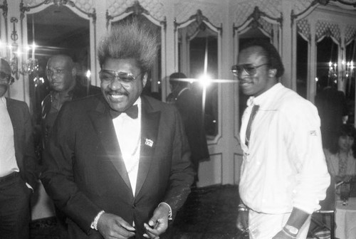 Don King standing with Michael Dokes at a press conference for the "Crown Affair" boxing event, Los Angeles, 1983