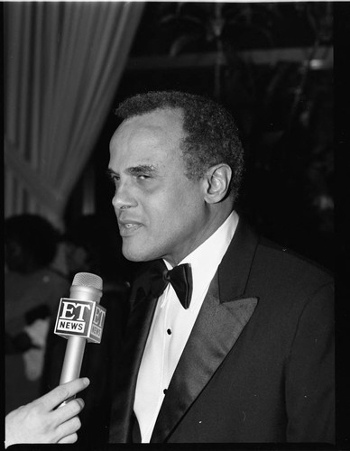 Harry Belafonte speaking with a newscaster at the TransAfrica and Artists and Athletes Against Apartheid benefit, Los Angeles, 1985