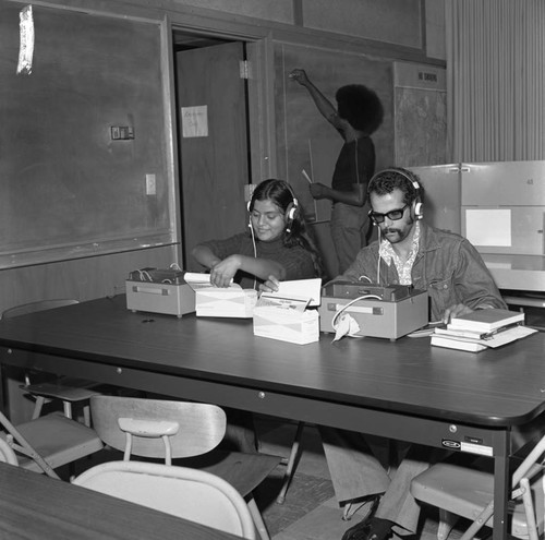 Students working with machines in a classroom at Compton College, Compton, 1972