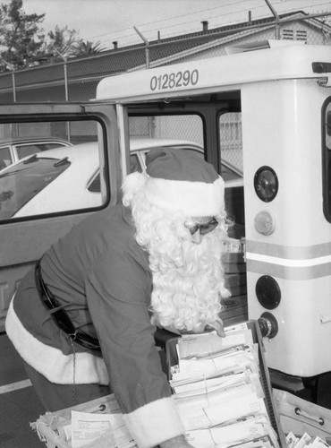 Jim Going dressed as Santa Claus loading mail into his truck, Los Angeles, 1983