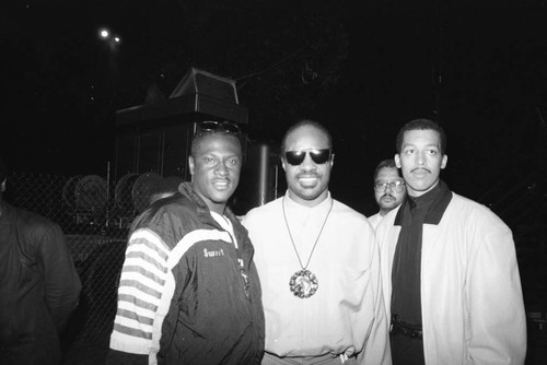 Stevie Wonder posing with two men at the Black Family Reunion in Exposition Park, Los Ageless, 1989