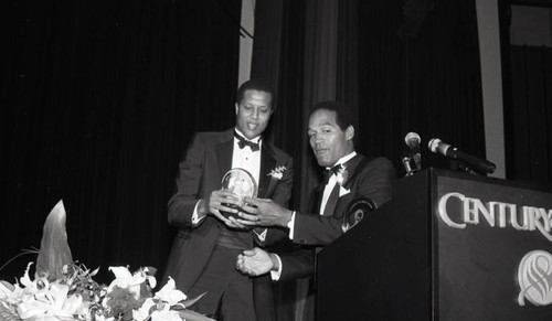 O.J. Simpson and Jamaal Wilkes holding an award from the Boys' Clubs of America, Los Angeles, 1987