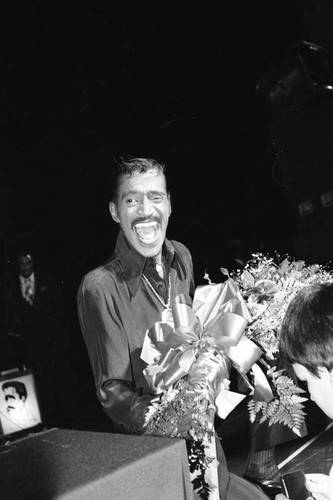 Sammy Davis Jr. laughing with a bouquet of flowers, Los Angeles, 1980