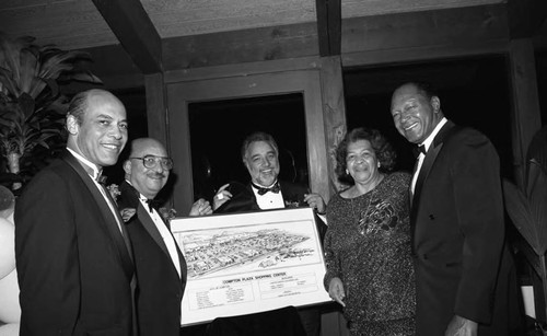 Danny Bakewell displaying a rendering of Compton Plaza Shopping Center during a formal event, Los Angeles, 1990