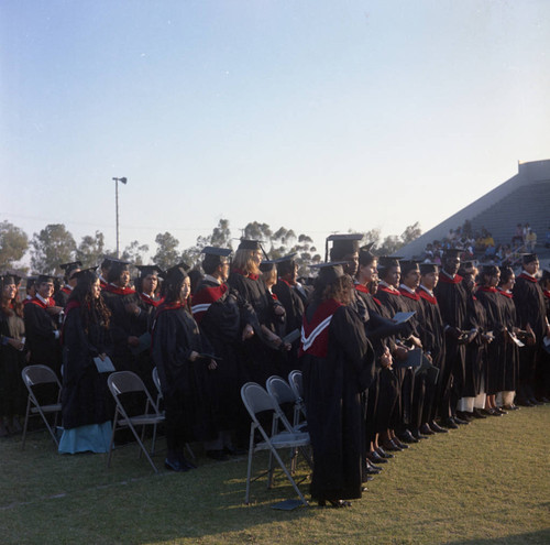 Compton College graduates standing at their seats during commencement, Compton, 1972