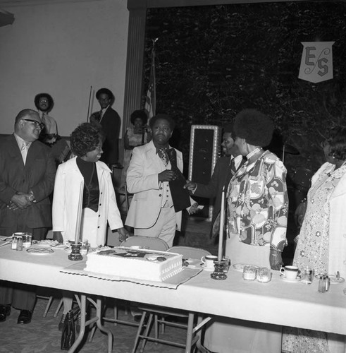 Michael Morris presenting a gift to an unidentified man during his birthday celebration, Compton, ca. 1974