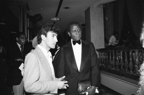 Sidney Poitier standing with an unidentified man at a Neighbors of Watts benefit, Los Angeles, 1982