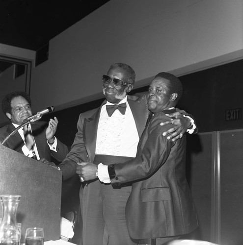 Herman English hugging Lee Elder at a dinner in Elder's honor, Los Angeles, 1977