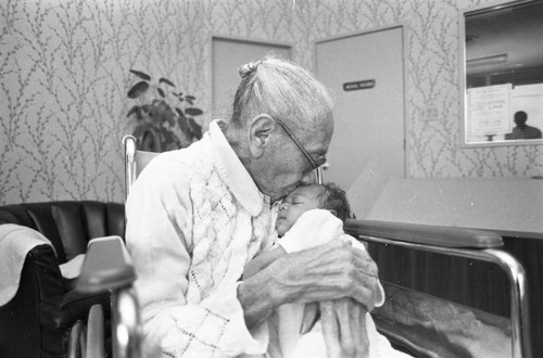 Mamie Smoot kissing an infant while celebrating her 100th birthday, Los Angeles, 1983