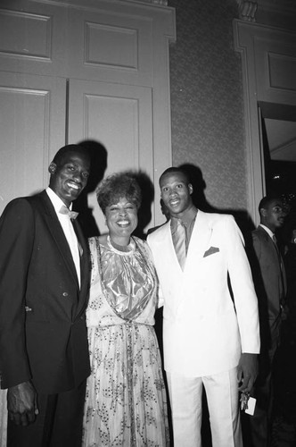 Diane Watson posing with Byron Scott and Michael Cooper at Magic Johnson's birthday party, Los Angeles, 1985