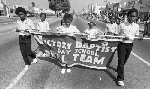 Victory Baptist Drill Team members carrying their banner in a parade, Los Angeles, 1982