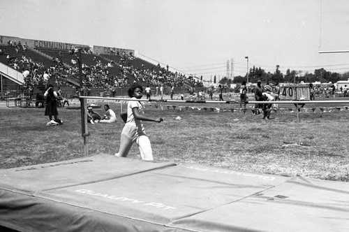 Young woman running to perform a high jump during the Compton Track and Field Championship, 1984