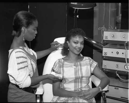 African American cosmetologist applying makeup to a customer, Los Angeles, 1984