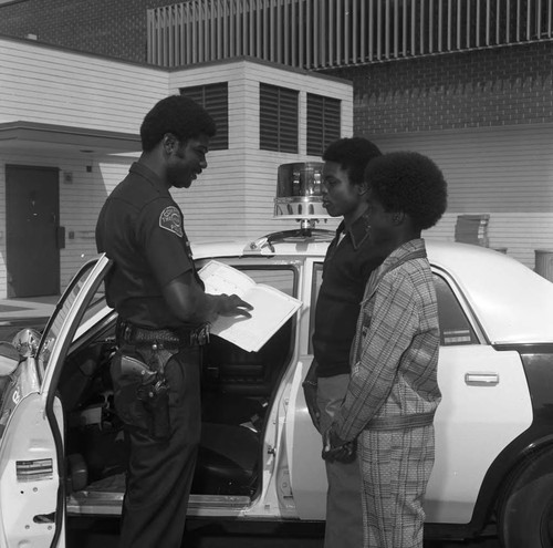 Police officer talking with two teenagers in the Police Explorer Scout program, Compton, 1973