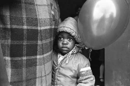 Child at Ritter Elementary School holding a balloon, Watts (Los Angeles, Calif.), 1983