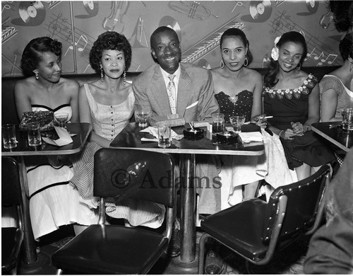 Black Dot McGee sitting with women at the Tiffany Club, Los Angeles, 1956