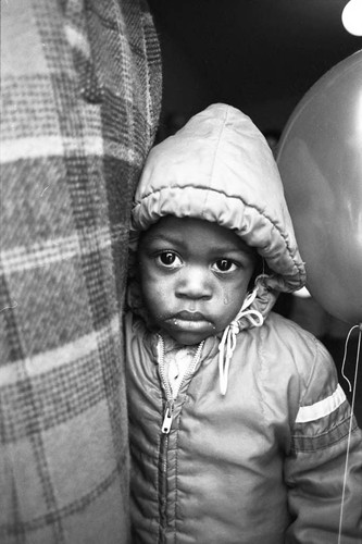 Child at Ritter Elementary School holding a balloon, Watts (Los Angeles, Calif.), 1983