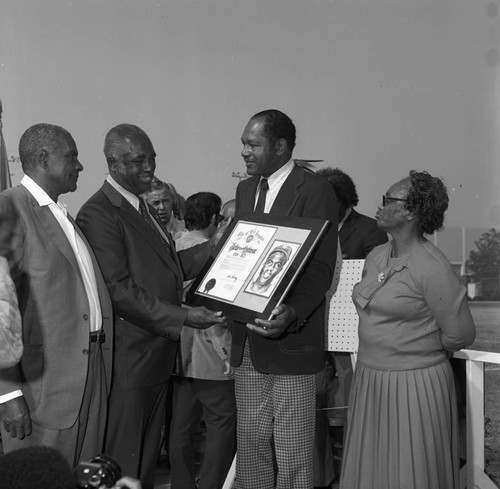 Tom Bradley holding a plaque at the opening of UCLA's Jackie Robinson Memorial Stadium, Los Angeles, 1989