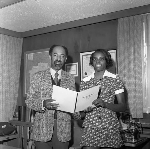 Dr. Abel Sykes and a young woman posing in his office at Compton College, Los Angeles, 1973