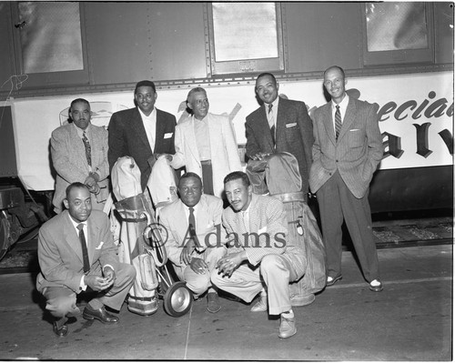 Men with gold clubs next to a train, Los Angeles, 1955