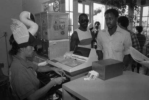 Clemon's restaurant cashier wearing a flamingo hat, Los Angeles, 1984