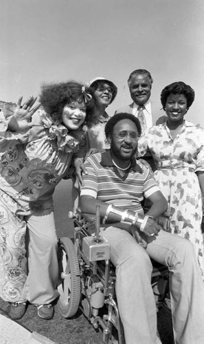 A women dressed as a clown posing with participants of a parade, Los Angeles, 1982