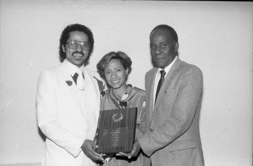 Sonny Harris holding an award with Iris Shelton at the Pied Piper Nightclub, Los Angeles, 1985