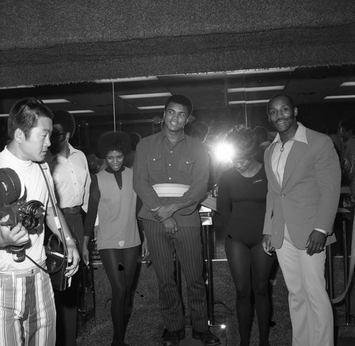 Muhammad Ali posing with Earl Maynard and others at a fitness center, Compton, 1973