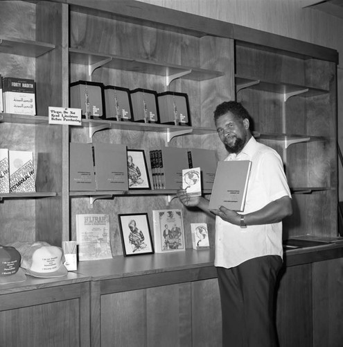 Samuel Kareem posing with copies of the International Library of Afro-American Life and History, Los Angeles, 1983