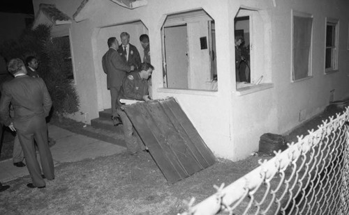 Police standing at the entry of a house during a publicized raid, Los Angeles, 1985