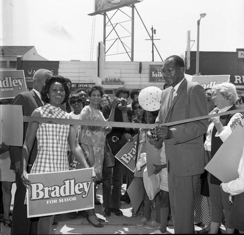 Tom Bradley cutting a ribbon with Yvonne Brathwaite Burke during his mayoral campaign, Los Angeles, 1969