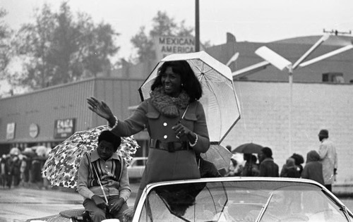 Doris Davis waving from a convertible during the Compton Christmas Parade, Compton, 1973