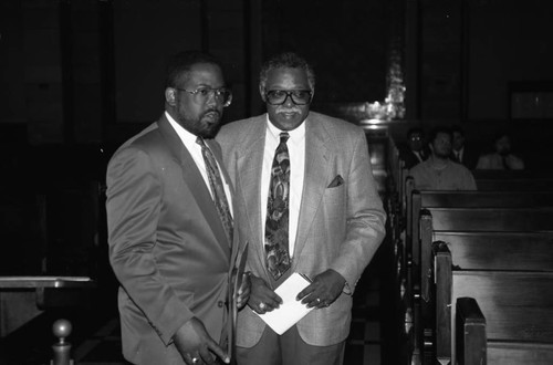 Guy Crowder and Mark Ridley-Thomas talking in the aisle of a church, Los Angeles, 1993