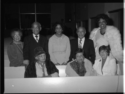 Diane Watson and Gilbert Lindsay posing with others among church pews, Los Angeles, 1983