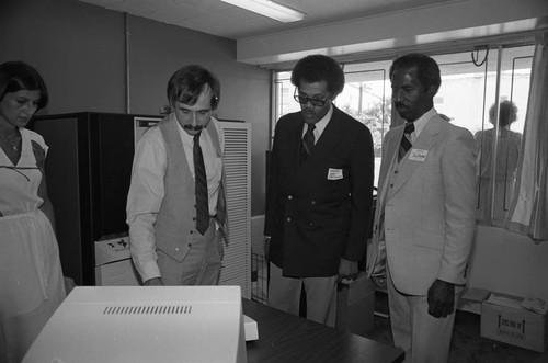 Donald Bohana and David Cunningham, Jr. examine computer operations, Los Angeles, ca. 1978