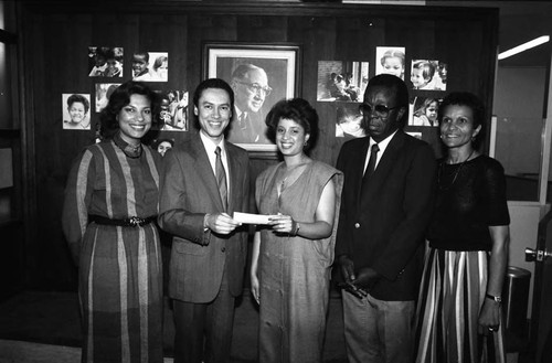 Paul C. Hudson holding a check with an unidentified young woman, Los Angeles, 1985