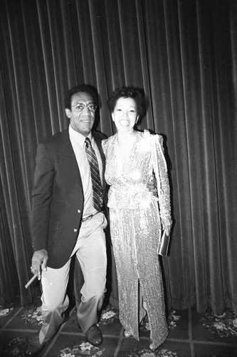 Bill Cosby posing with an unidentified woman at a Neighbors of Watts benefit, Los Angeles, 1982