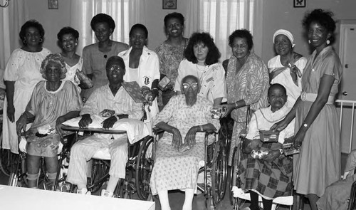 Men and women in wheelchairs posing with care givers, Los Angeles, 1989