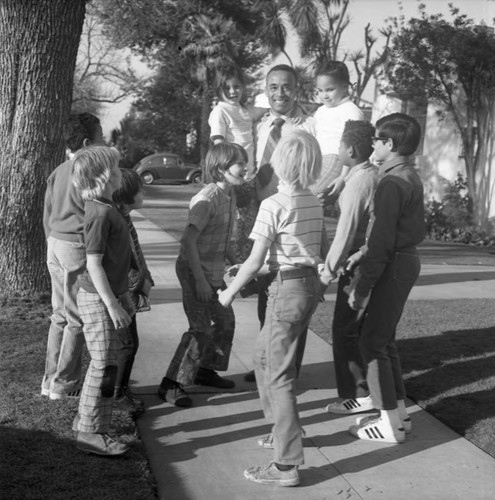 Arnett Hartsfield standing on a neighborhood sidewalk surrounded by children, Los Angeles, 1971