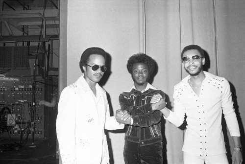 Three men posing together back stage during KGFJ's Soul Search event, Los Angeles, 1975