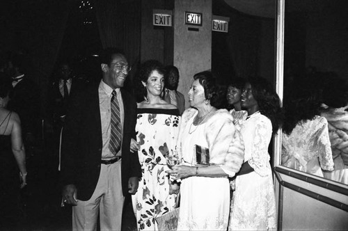 Bill Cosby and his wife Camille talking with Gertrude Gipson at a Neighbors of Watts benefit, Los Angeles, 1982