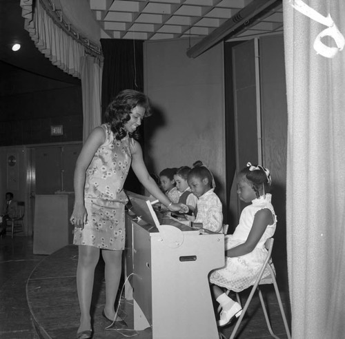 Woman talking to a girl at a piano at Compton Community College, Compton, 1972