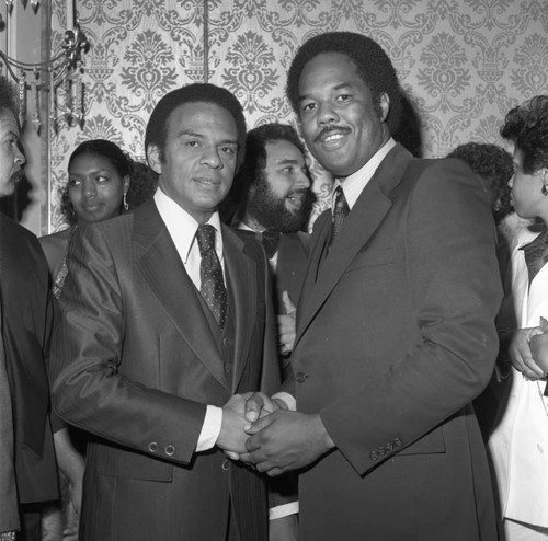 Andrew Young posing with a guest at a Brotherhood Crusade dinner, Los Angeles, 1978