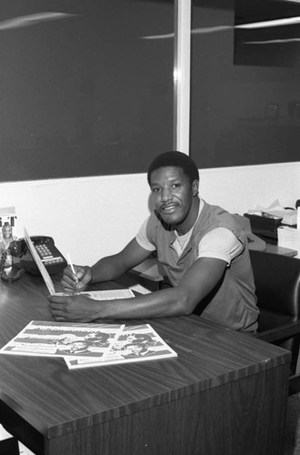 Roy Mabry sitting with his "Black Achievements in America" calendar, Los Angeles, 1986