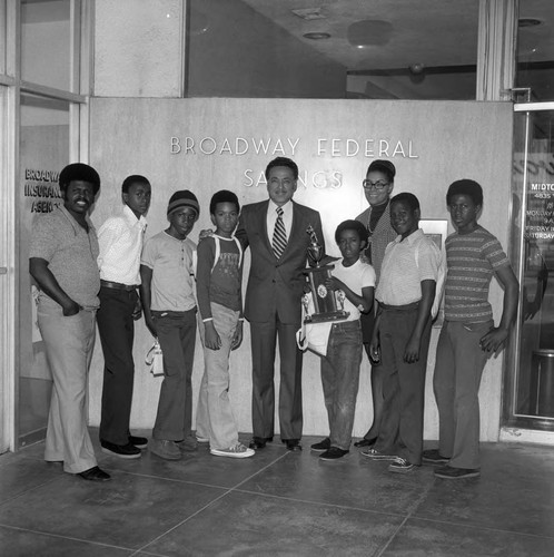 Elbert T. Hudson posing with the Broadway Braves and their trophy, Los Angeles, 1974